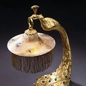 A table lamp with the base cast as a peacock holding the glass shade from its mouth, c
